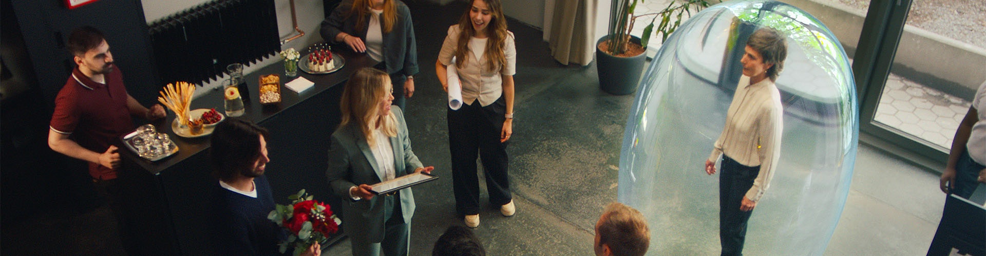 A work get-together: An older woman is surrounded by a bubble that represents her hearing loss, and she does not hear that she is receiving an award.