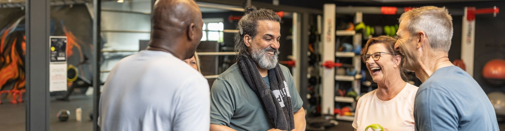 Four adults are at a group fitness lesson, and the adult with the cochlear implant can hear and join in on the conversation and laughter.